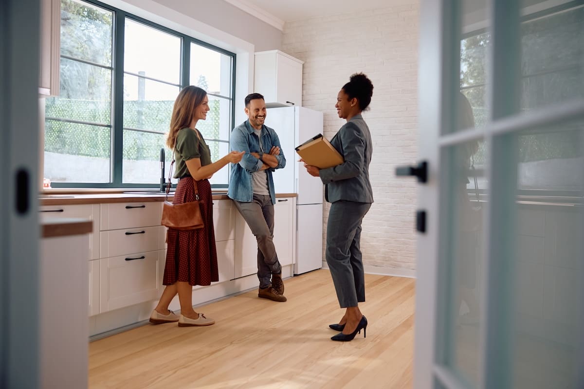 Ingatlanközvetítő körbevezeti a fiatal párt az ingatlanban.