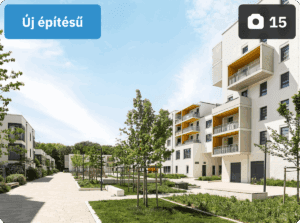 A képen egy modern, új építésű lakópark látható rendezett sétánnyal, zöld növényzettel és többemeletes társasházakkal, melyek erkélyei sárga színű kiemelésekkel díszítettek. A bal felső sarokban kék címke jelzi, hogy az ingatlan „Új építésű”, míg a jobb felső sarokban egy kamera ikon és a „15” szám a feltöltött képek mennyiségét mutatja.