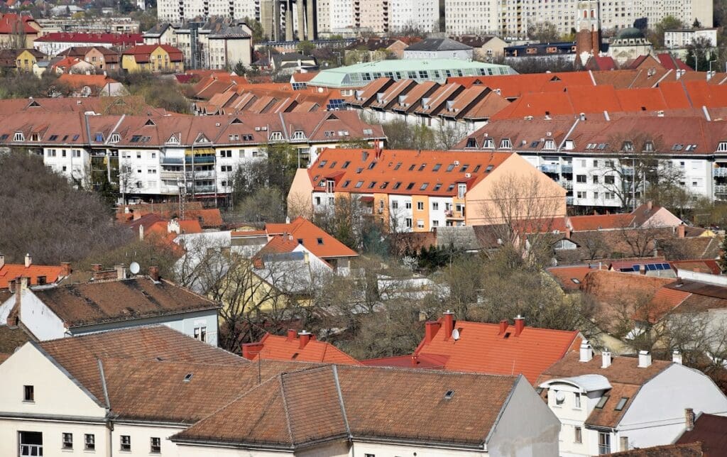 Városi kilátás: sűrűn beépített terület különböző színű és formájú háztetői.