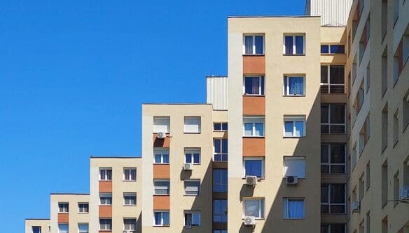 Panelház homlokzata kék ég alatt, több emeletes lakóépület ablakokkal és klímaberendezésekkel. A panellakások iránti kereslet kilőtt az Otthon Start program bejelentése óta.