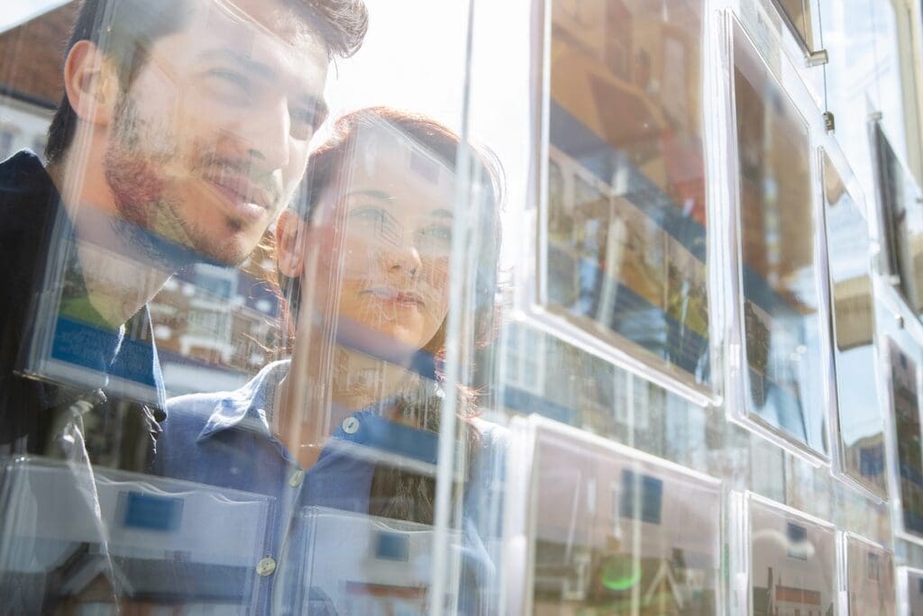 Fiatal pár ingatlanirodai kirakat előtt, eladó lakások és házak hirdetéseit nézi. Az Otthon Start bejelentése óta kiugró az ingatlanpiaci érdeklődés Magyarországon.