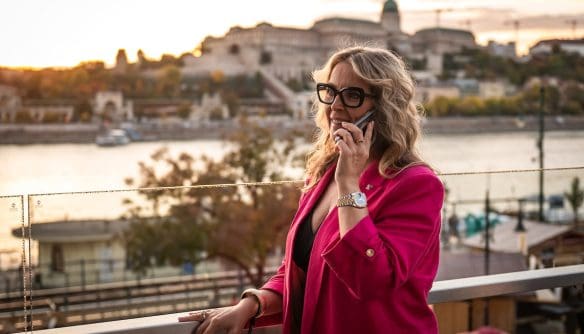Vörös Eszter, iCompass díjazott ingatlanközvetítő telefonál a Budapest Marriott Hotel teraszán, a Comferencia 2025-ön.
