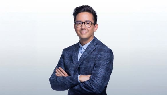 Debrecen ingatlanpiacán tevékenykedő Tran Balázs ingatlanközvetítő portréja szürke színátmenetes háttér előtt.