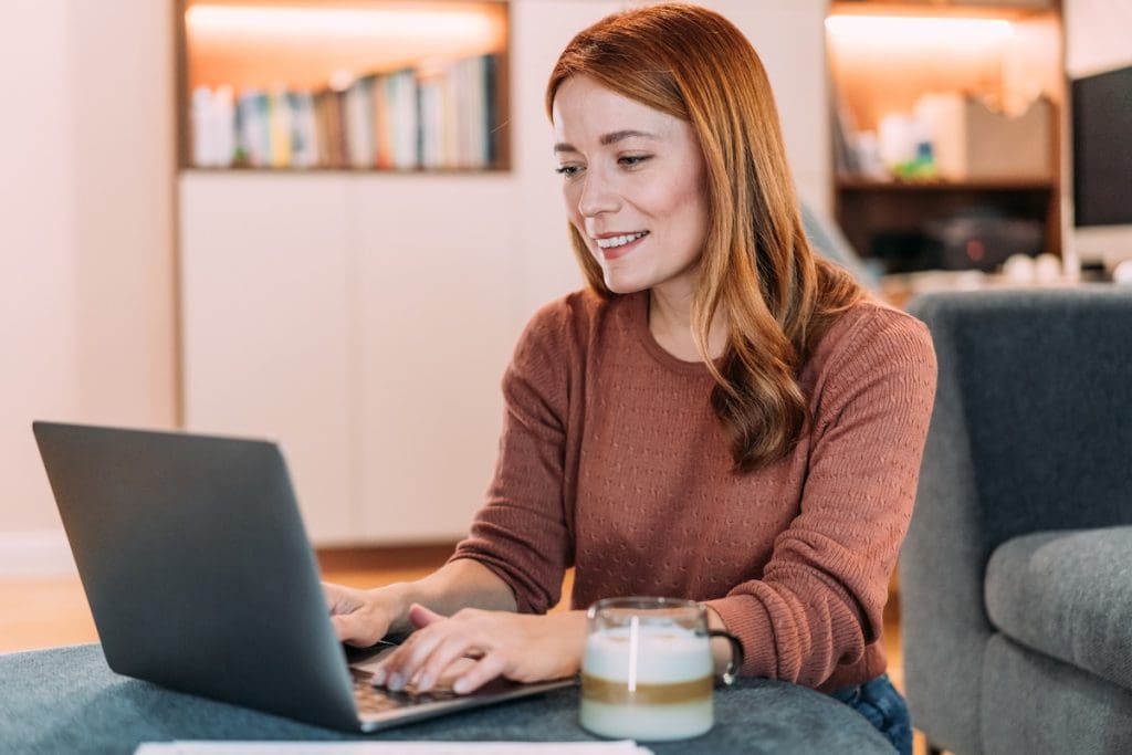 Fiatal nő a laptopján nézeget ingatlanhirdetéseket.