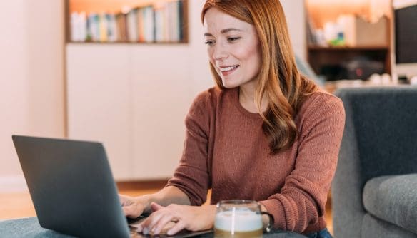 Fiatal nő a laptopján nézeget ingatlanhirdetéseket.