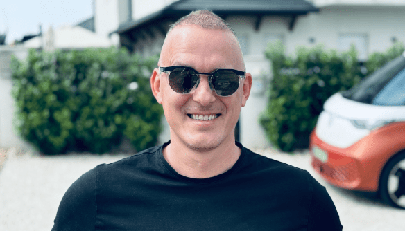 Barna József ingatlanközvetítő portréja. József fekete napszemüvegben és pólóban áll, mögötte elhomályosított utcakép.