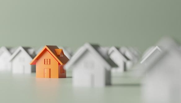 Minimalista illusztráció, amelyen egy narancssárga házmodell emelkedik ki a háttérben elmosódó, fehér házak sorából, az ingatlanpiaci verseny és az egyedi lehetőségek szimbolizálására.
