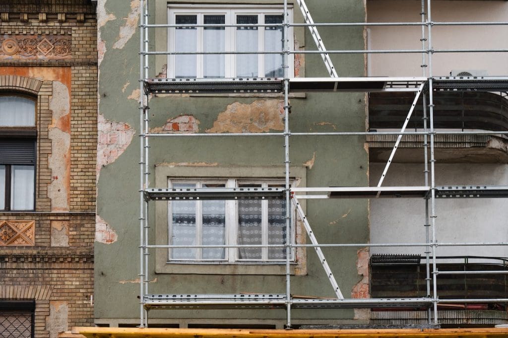 Régi budapesti lakóépület sérült homlokzata. Az épület fel van állványozva, feltehetőleg felújítási munkák céljából.