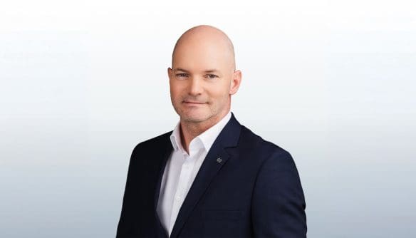 Nagy Roland Bruno, Telki és a budai agglomeráció ingatlanközvetítőjének portréja szürke színátmenetes háttér előtt.