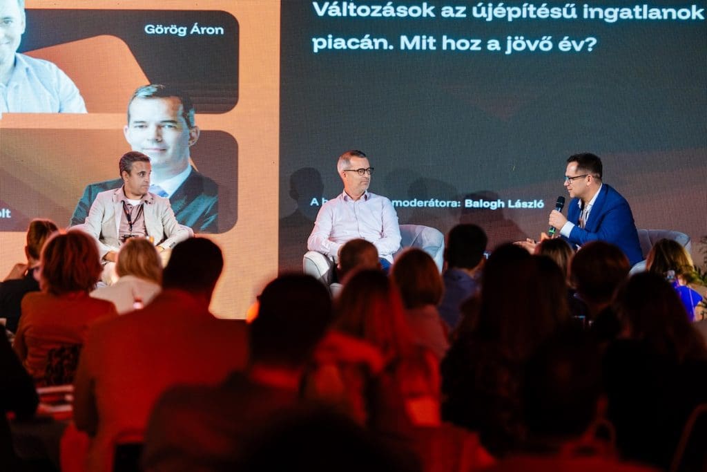 Balról jobbra: Görög Áron (Cordia), Nagy Zsolt (Metrodom) és Balogh László (ingatlan.com) a Comferencia 2026. színpadán. A képen épp Balogh László kérdez valamit a kerekasztal résztvevőitől.